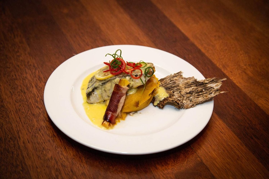 Paperbark smoked local barramundi on a white plate.