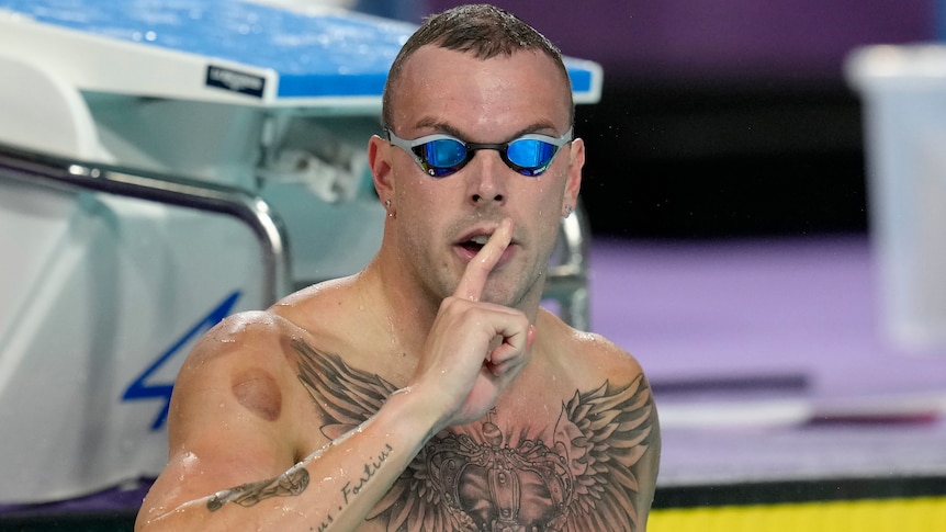 Kyle Chalmers holds a finger to his lips in the Commonwealth Games pool.