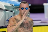 Kyle Chalmers holds a finger to his lips in the Commonwealth Games pool.