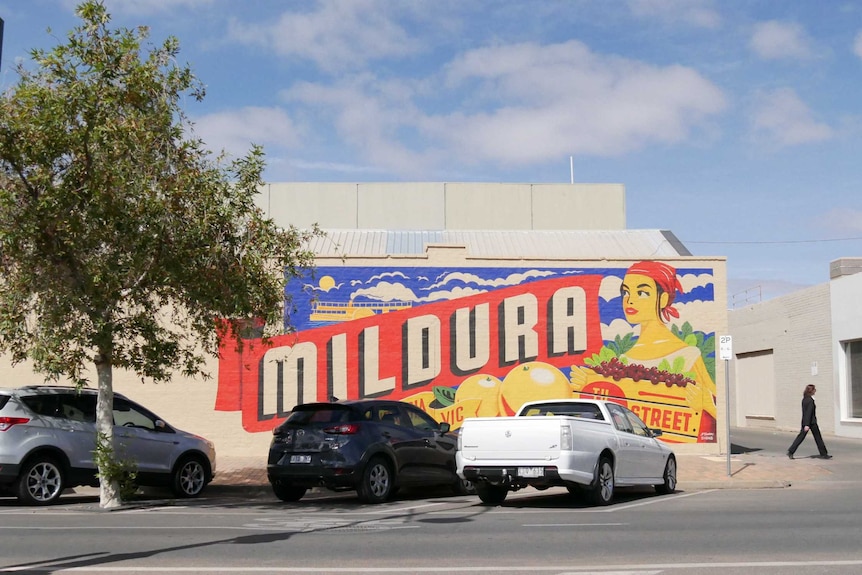 A mural in Mildura of a woman with a bandanna holding a box of grapes, in front of giant oranges, saying Mildura in big letters.
