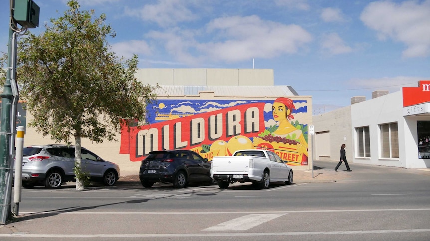 A mural in Mildura of a woman with a bandanna holding a box of grapes, in front of giant oranges, saying Mildura in big letters.