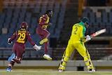 A West Indian bowler leaps in the air joyously as the Australian batsman he has dismissed turns to trudge off.