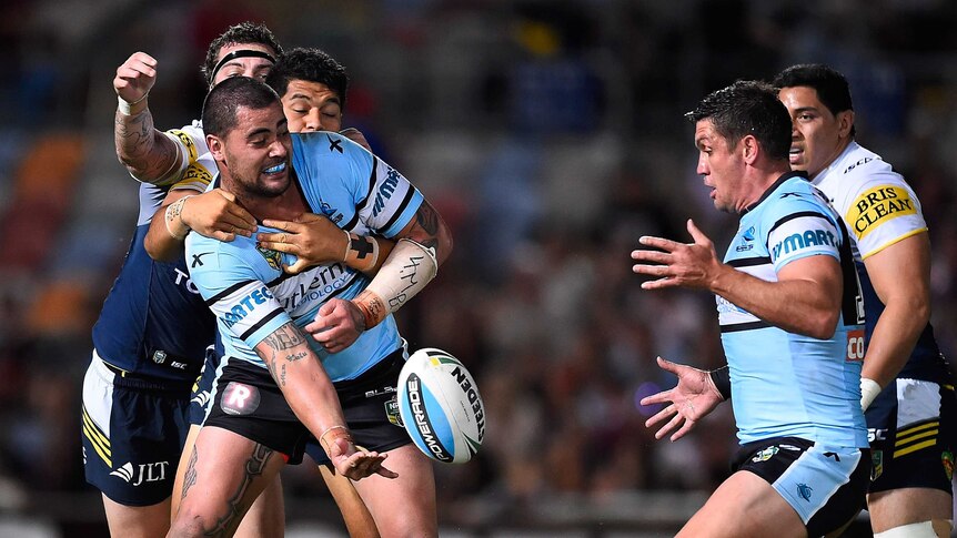 Andrew Fifita of the Sharks passes the ball as he is tackled