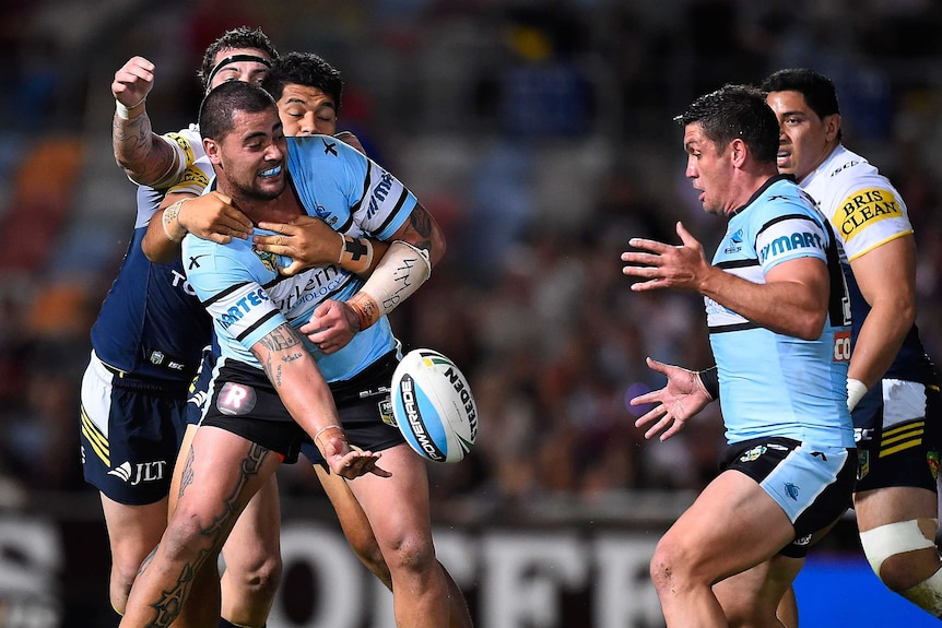 Andrew Fifita of the Sharks passes the ball as he is tackled