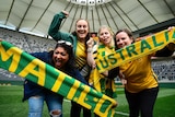 Four women celebrate their favourite soccer team at an oval in Sydney