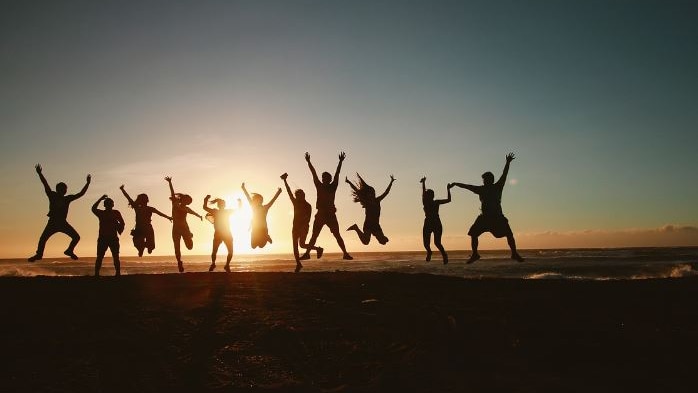 Photo of a group of people jumping into the air at sunset 