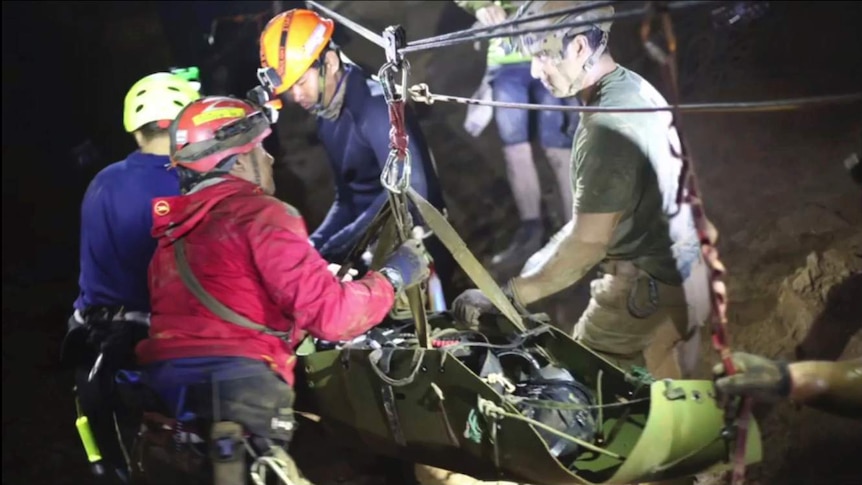 Rescuers hold an evacuated boy inside the Tham Luang cave.