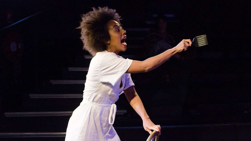 Production photograph of actor Ayeesha Ash during rehearsal of Brown Skin Girl, shouting across the stage with comb in hand.