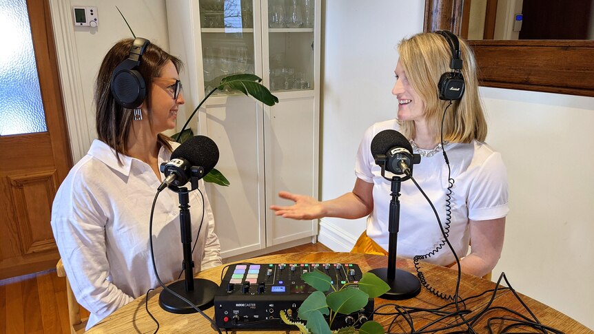 Two women sitting in a loungeroom with audio equipment chatting