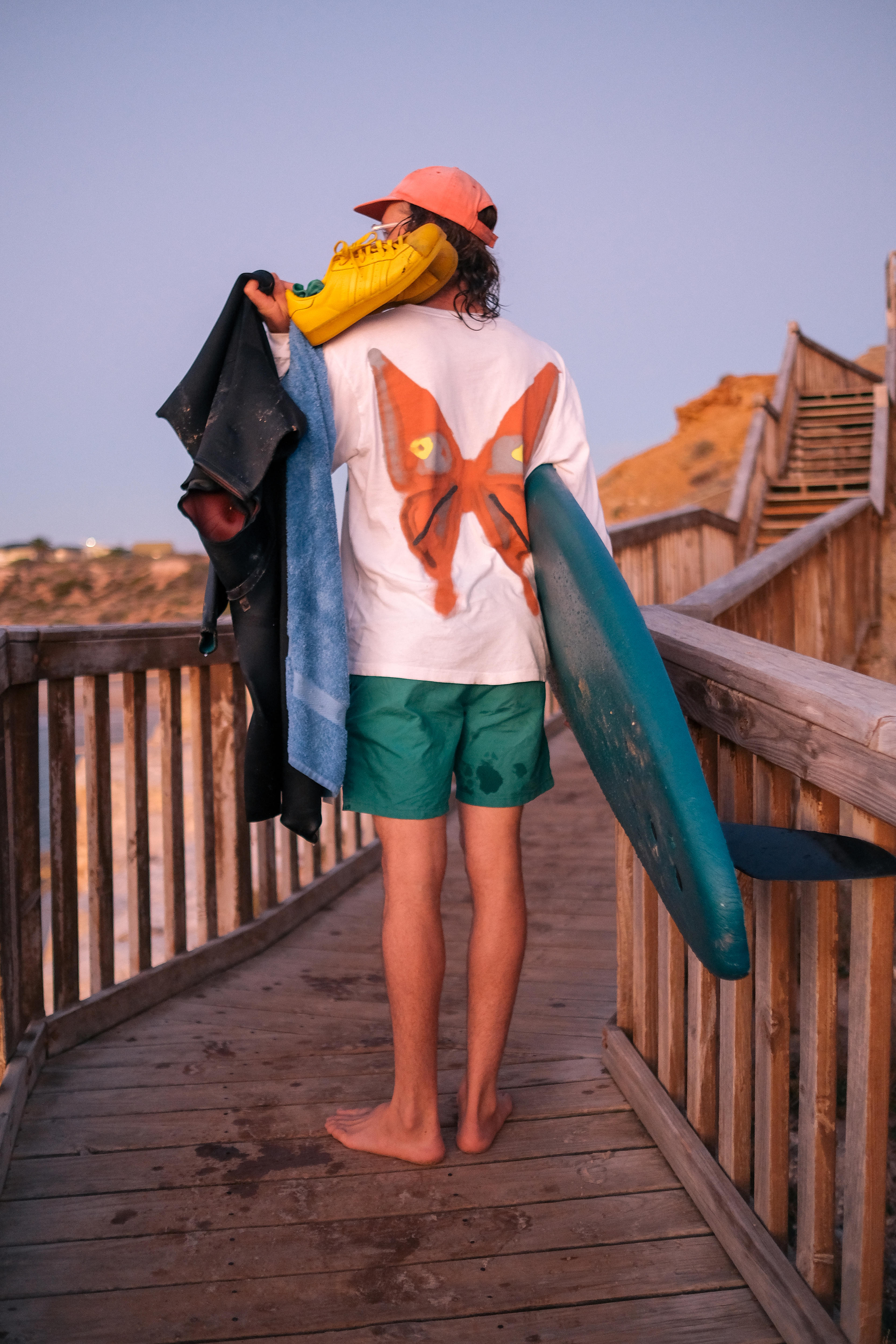 Artist Henry leaves the beach carrying his surfboard, towels, shoes and wetsuit 