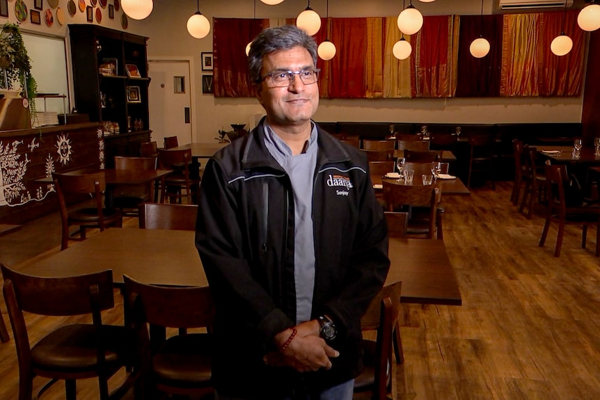 Man wearing a black jacket standing in a restaurant. 