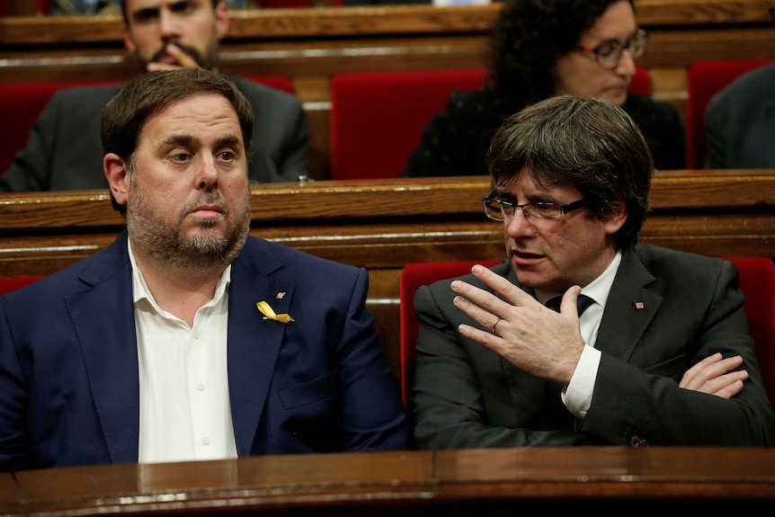 Former Catalan Vice President Oriol Junqueras sits to the left of former President Carles Puigdemont as they talk in parliament.
