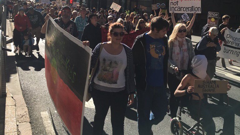 A crowd of people marches down a street in Brisbane's CBD.