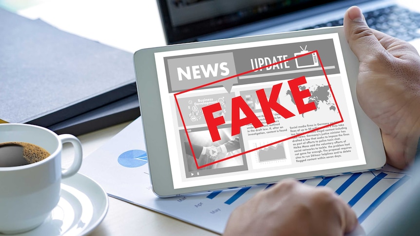 Fake news concept: Man reading news on a table with stamp across saying 'Fake'