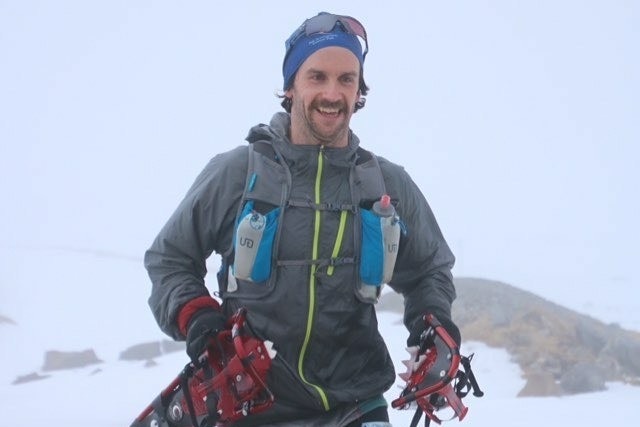 man in thermal clothes and beanie running in snow with smile 