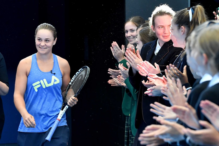 Ashleigh Barty greets young fans as she walks onto the court at an event in Brisbane