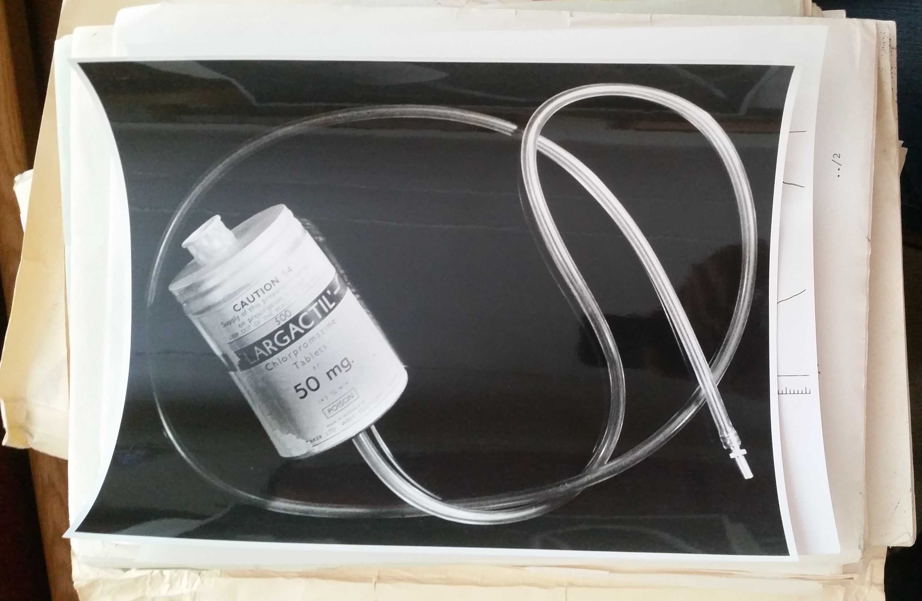 A black-and-white photo of a penile plethysmograph: a medical container with a long fitted rubber tube.