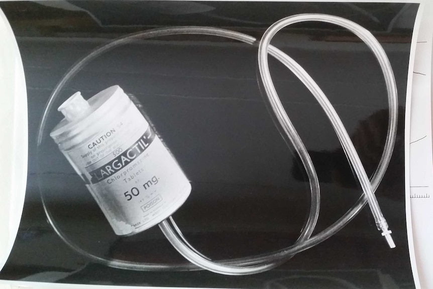 A black-and-white photo of a penile plethysmograph: a medical container with a long fitted rubber tube.