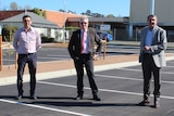 Three men stand in a car park