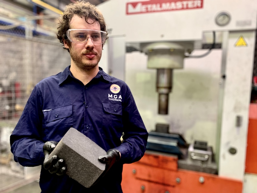 Alex Post stands holding one of MGA Thermal's heat storing alloy 'bricks'.