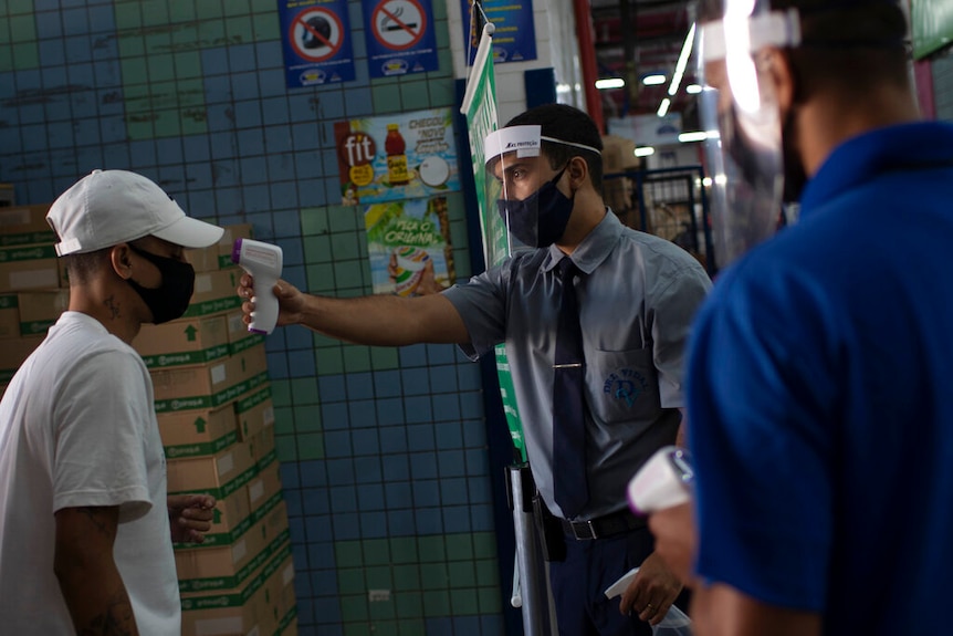 A customer gets his temperature checked before entering the Madureira Market amid the new coronavirus pandemic.