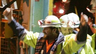 Todd Russell (L) and Brant Webb wave as they emerge from the Beaconsfield Gold Mine lift