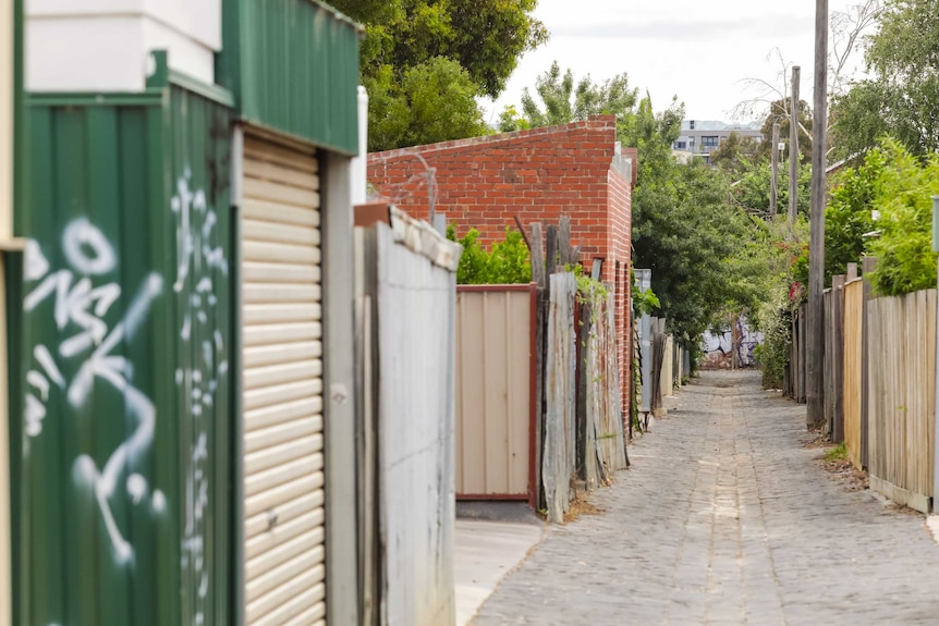 A cobblestone alleyway separates rows of house in a street in Melbourne.