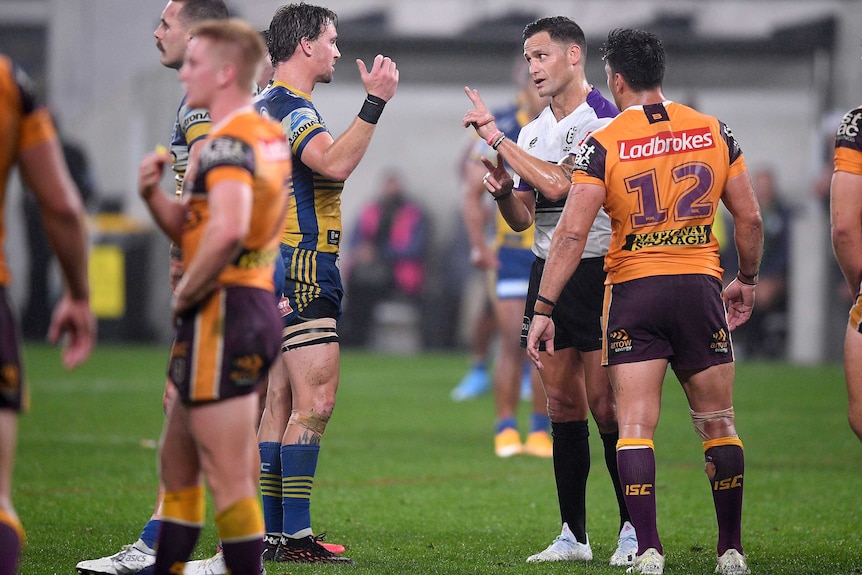 Rugby league players with his hand in the air arguing with the referee about a decision made during a game