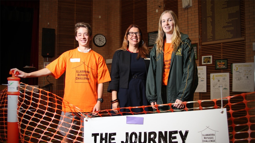 Jeremy Eager, Clare Matthews and Ruby Meiers stand in front on an orange fence sign that says 'the Journey'.