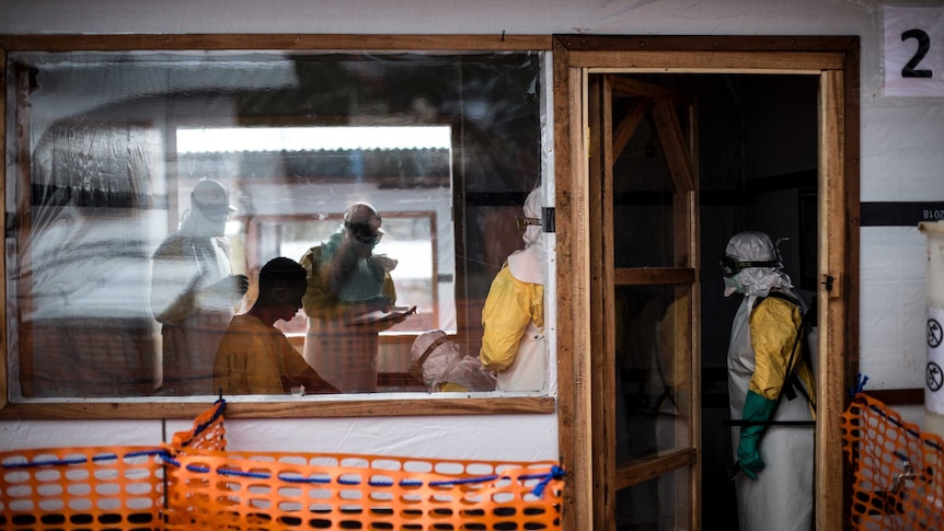 People wearing protective clothing from Ebola discussing treatment.