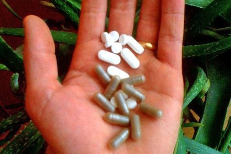 A hand holds herbal supplements.