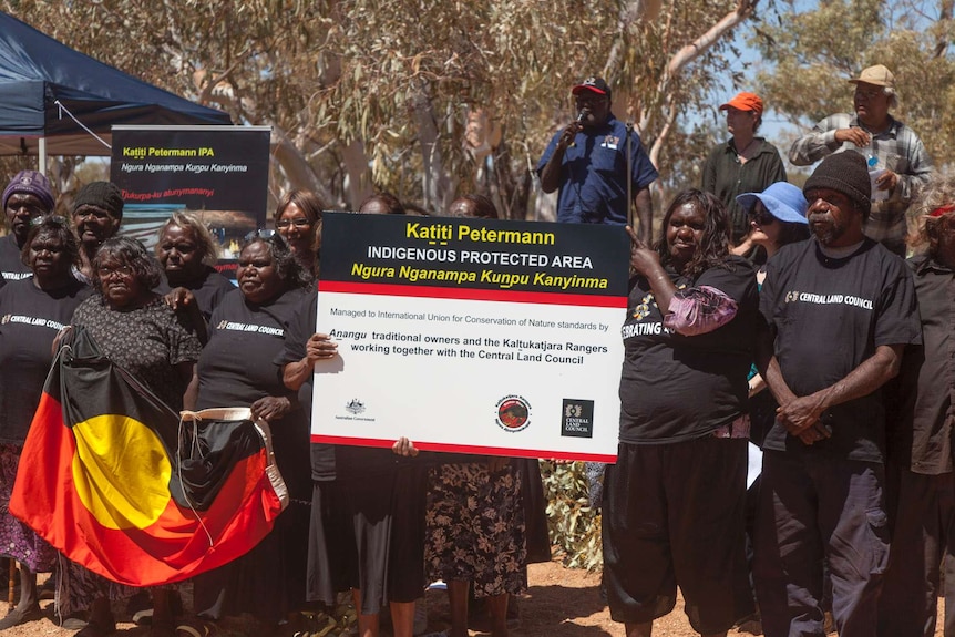 The Anangu people in Central Australia hold up a sign showing IPA