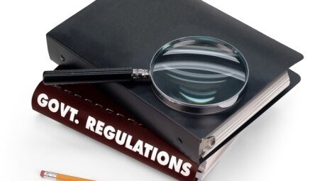 Government regulations book with magnifying glass (Thinkstock)