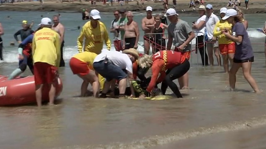 Lifesavers surround a man on the beach in Lorne.