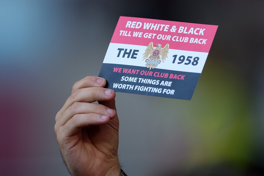 A hand holds up a card saying THE 1958 in red white and black