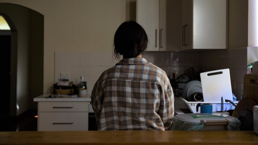 A shot from behind of Alyssa standing in her kitchen.