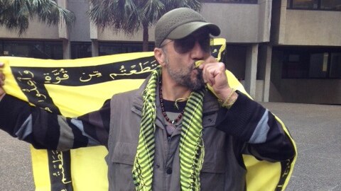 Mahdi Naseri kisses his Hezbollah flag at protests in Sydney