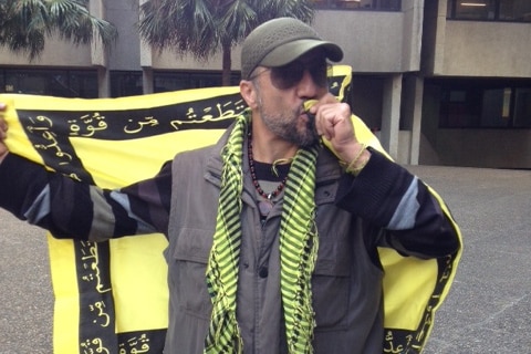 Mahdi Naseri kisses his Hezbollah flag at protests in Sydney