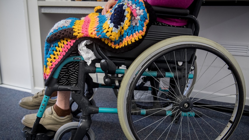 Close up of older woman with a patterend blanket in her wheelchair.