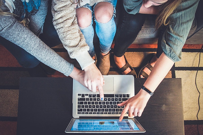 Three young people looking at something on a laptop screen