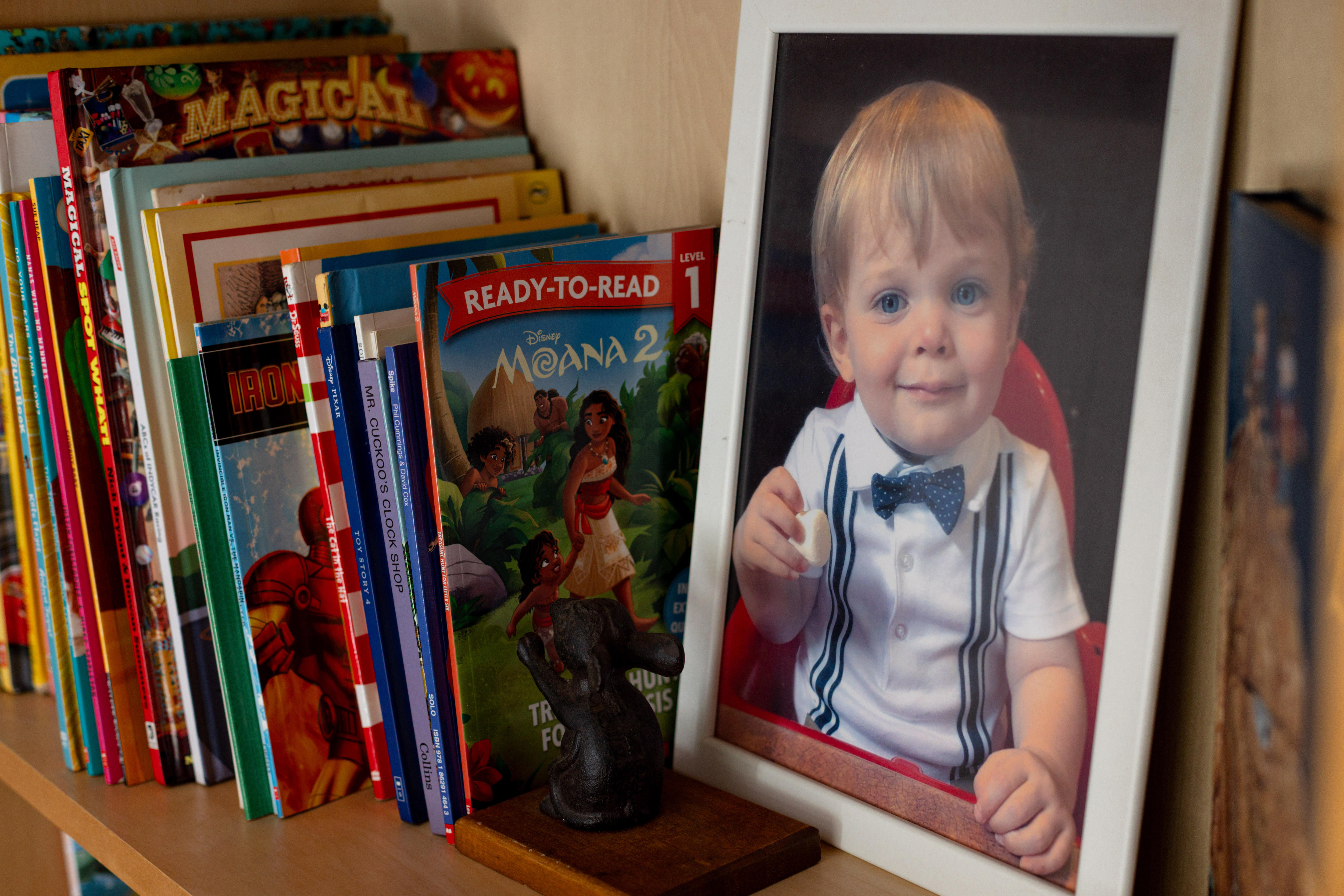 A photograph of a boy on a shelf with children's books