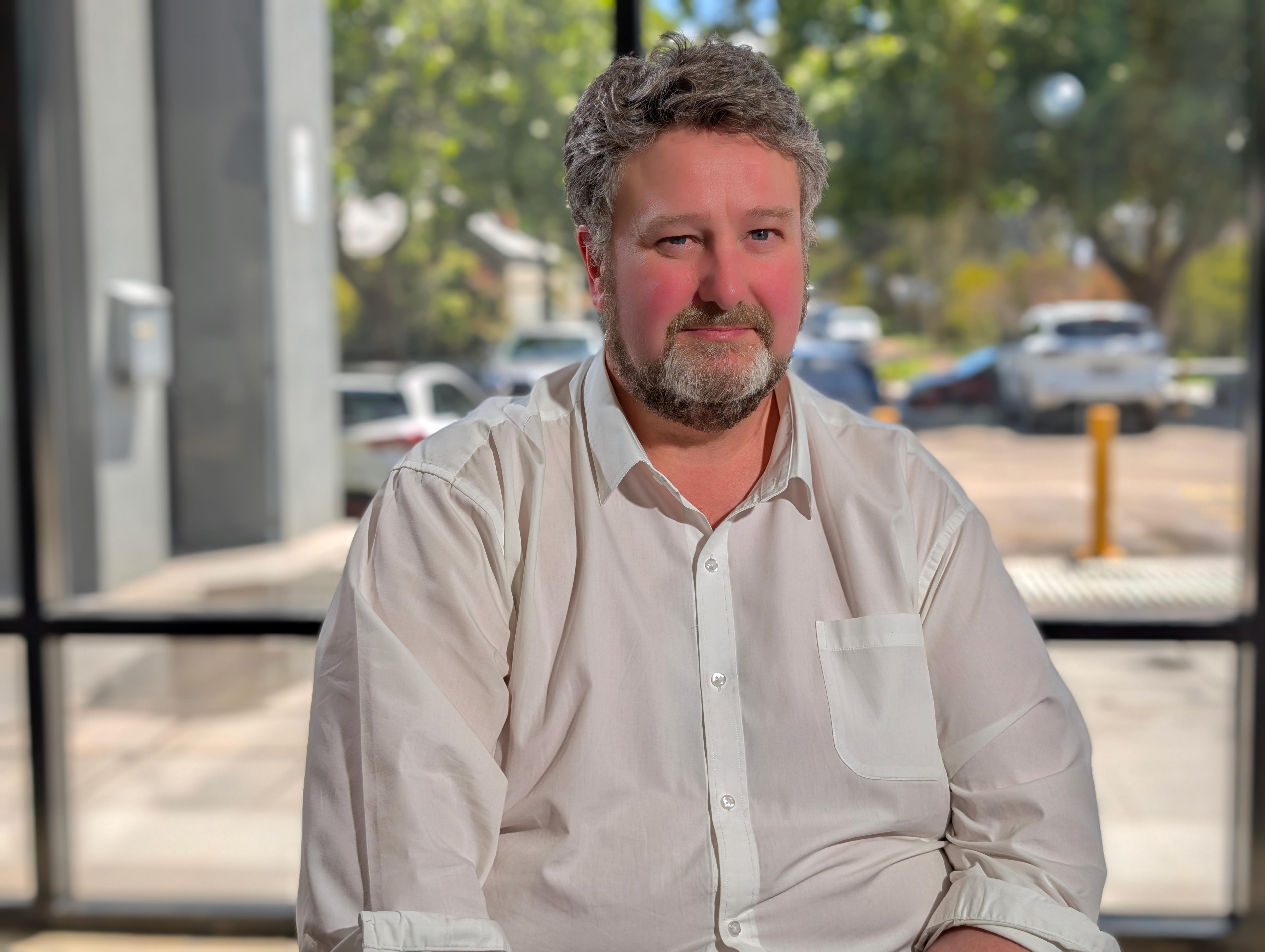 Homem barbudo de camisa branca. 