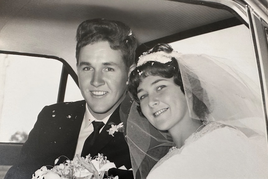 A black and white wedding photo of a couple in a car.