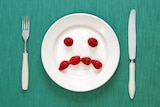 A plate with a sad face made out of berries.