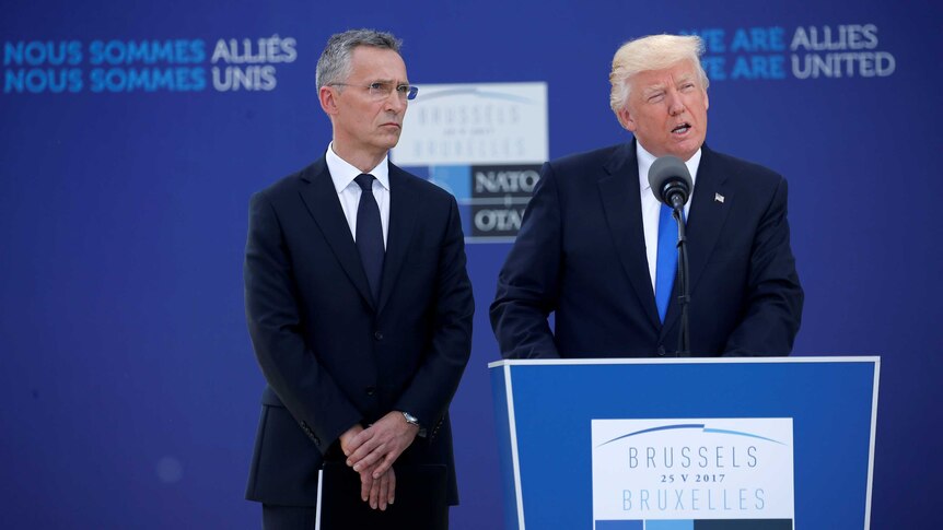 Donald Trump delivers a speech from a lectern with Jens Stoltenberg standing next to him.