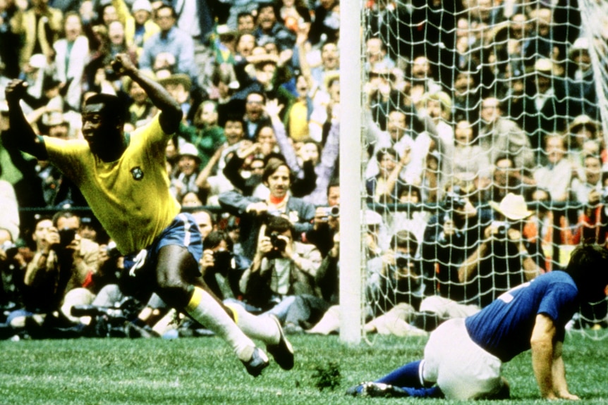 Pele runs with his arms up with a player on the ground beside him