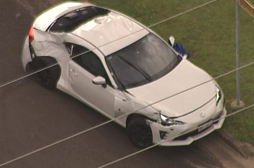 A badly damaged car sits on the side of the road