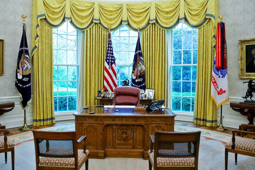 The Resolute Desk, sitting empty in the Oval Office, surrounded by empty chairs