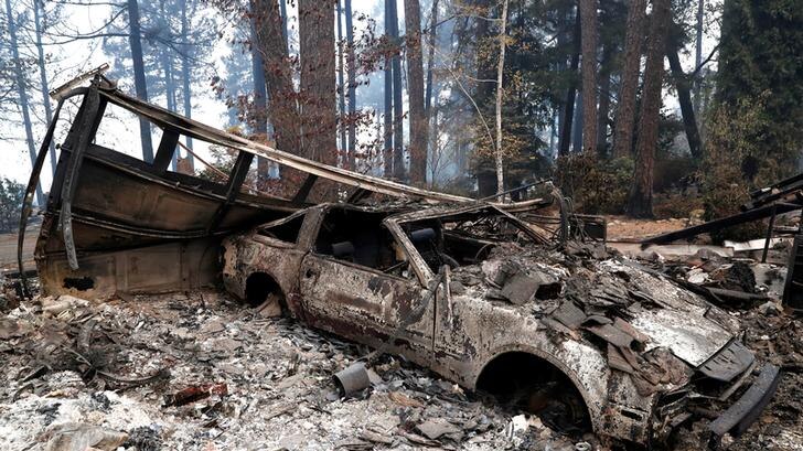 A burned out car destroyed by wildfires in Paradise, California, rests among ashes