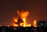 Smoke and flames rise in the distance following Israeli airstrikes on a building in Gaza City.
